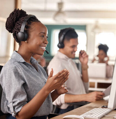 Call center, black woman and smile at computer for telemarketing, sales and support. Professional female consultant or agent with a headset and team for customer service, crm and help desk or advice